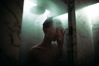 Digital composite image of young man standing in bathroom