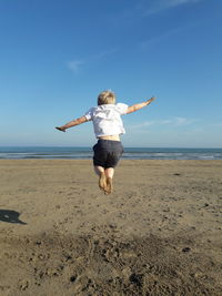 Rear view of girl jumping on beach