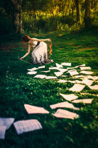 Woman collecting papers on field