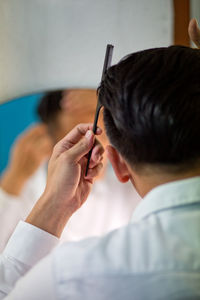 Close-up of man combing hair at home