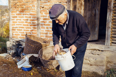 Man holding bucket and container while standing on land