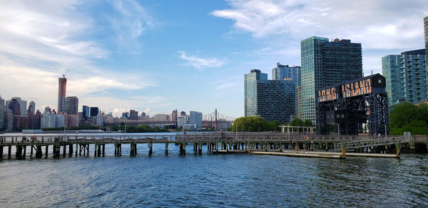 River by modern buildings against sky in city