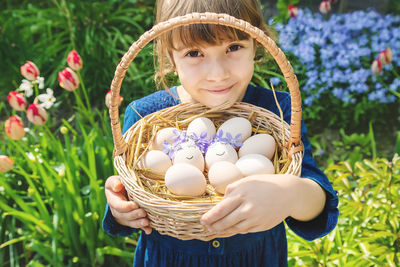 Portrait of cute girl holding eggs in basket