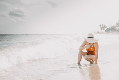 Rear view of woman sitting at beach