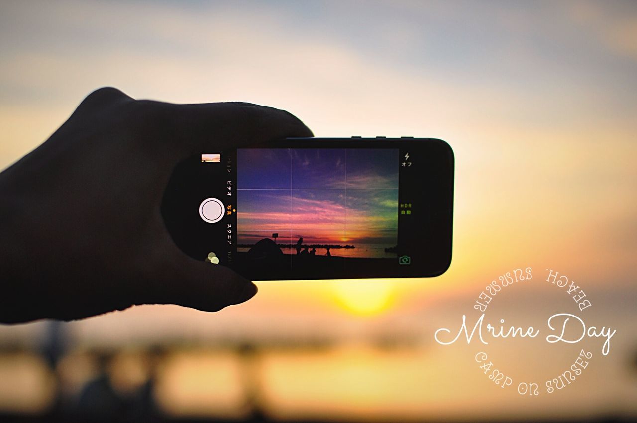 person, communication, holding, focus on foreground, part of, photography themes, close-up, cropped, sky, technology, human finger, photographing, leisure activity, text, sunset, camera - photographic equipment, lifestyles