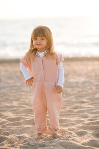 Smiling pretty little child 2-3 year old playing at beach over sea at background in light outdoors