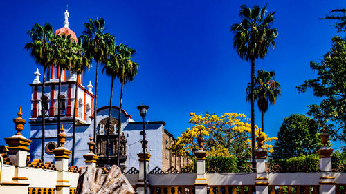 Low angle view of san pedro apostol church against blue sky, surrounded by white wall