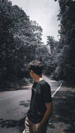 Rear view of boy standing against trees