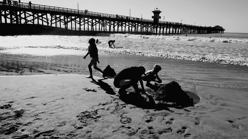 Silhouette people on beach against sky