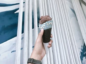 Cropped hand of person holding ice cream cone outdoors