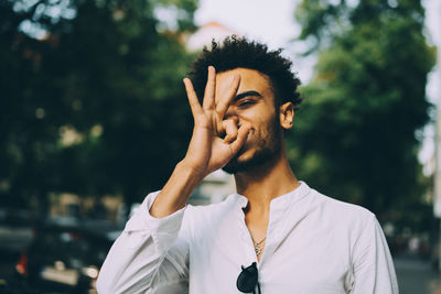 Young man gesturing while standing in city