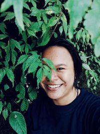 Portrait of smiling young woman by plants