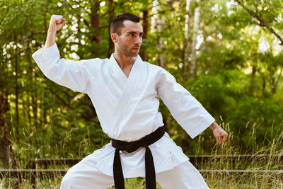 Man with karategi practicing martial arts in the forest