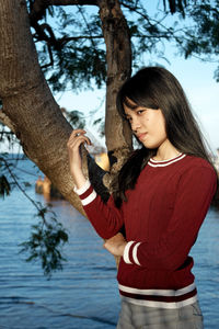 Portrait of girl standing against tree and lake