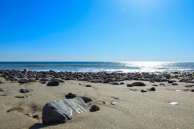 Scenic view of beach against clear blue sky