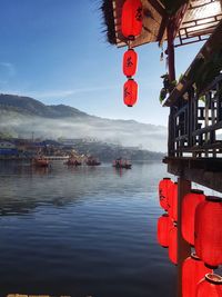 Red lanterns hanging over river against sky