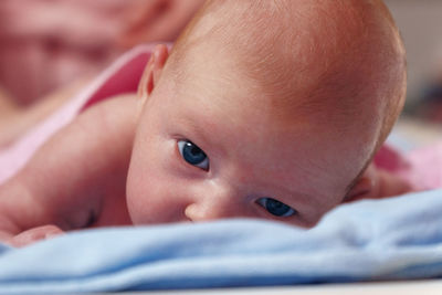 Close-up of cute baby boy lying on bed at home