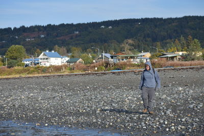 Man with umbrella walking on street by river