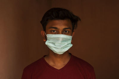 Portrait of young man with mask against wall
