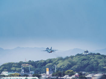 Airplane flying over mountains against blue sky