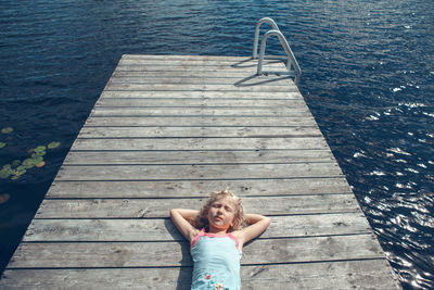 High angle view of girl relaxing on pier over water