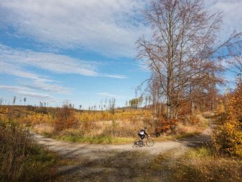 Rear view of man walking on field against sky