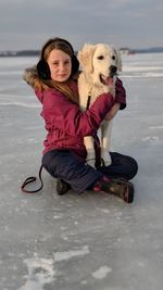 Portrait of woman with dog sitting on beach against sky