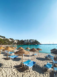 Deck chairs on beach against clear blue sky