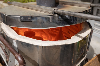 A red hot raku furnace with half open lid and raku ware pots visible