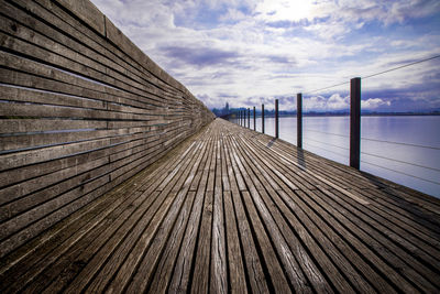 Surface level of wooden pier over sea against sky