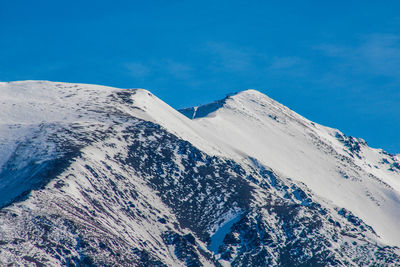 Scenic view of snowcapped mountains against blue sky