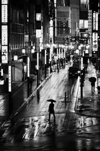 People walking on wet street in city during rainy season