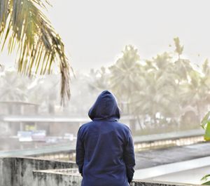 Rear view of person standing against palm tree