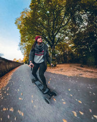 Young woman skateboarding on road during autumn