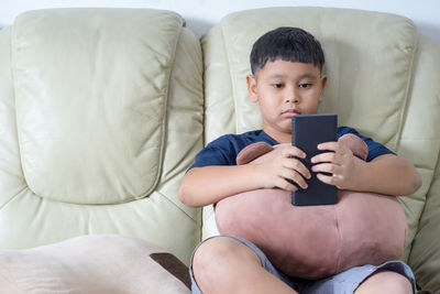 High angle view of boy sitting on sofa at home