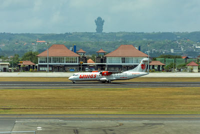 Airplane on airport runway against sky