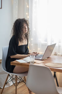 Woman using phone while sitting on table