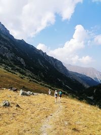 Rear view of people walking on mountain against sky