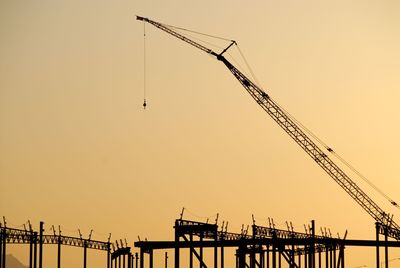Silhouette cranes against clear sky during sunset