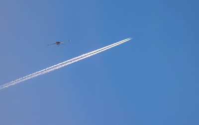 Low angle view of airplane flying against clear blue sky