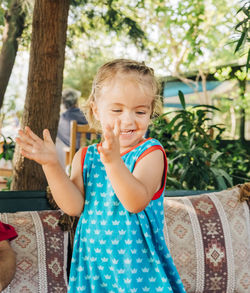 Cute smiling girl clapping while standing in backyard