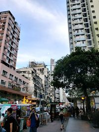 People on city street by buildings against sky