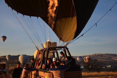 People on hot air balloon against sky