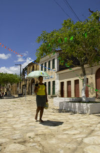 Woman standing by building against sky in city