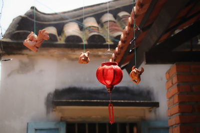 Close-up of hand holding red bell hanging outside building