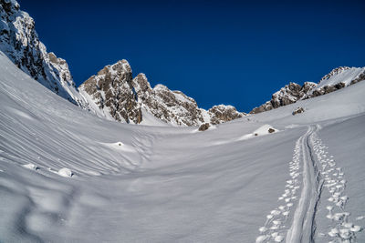 Scenic view of snowcapped mountains against clear blue sky