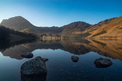 Scenic view of lake and mountains against clear blue sky