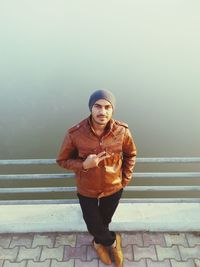 High angle portrait of man leaning by railing on bridge over sea