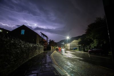 Road amidst buildings against sky at night