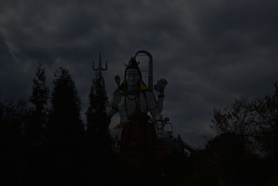 Low angle view of silhouette sculpture on building against sky